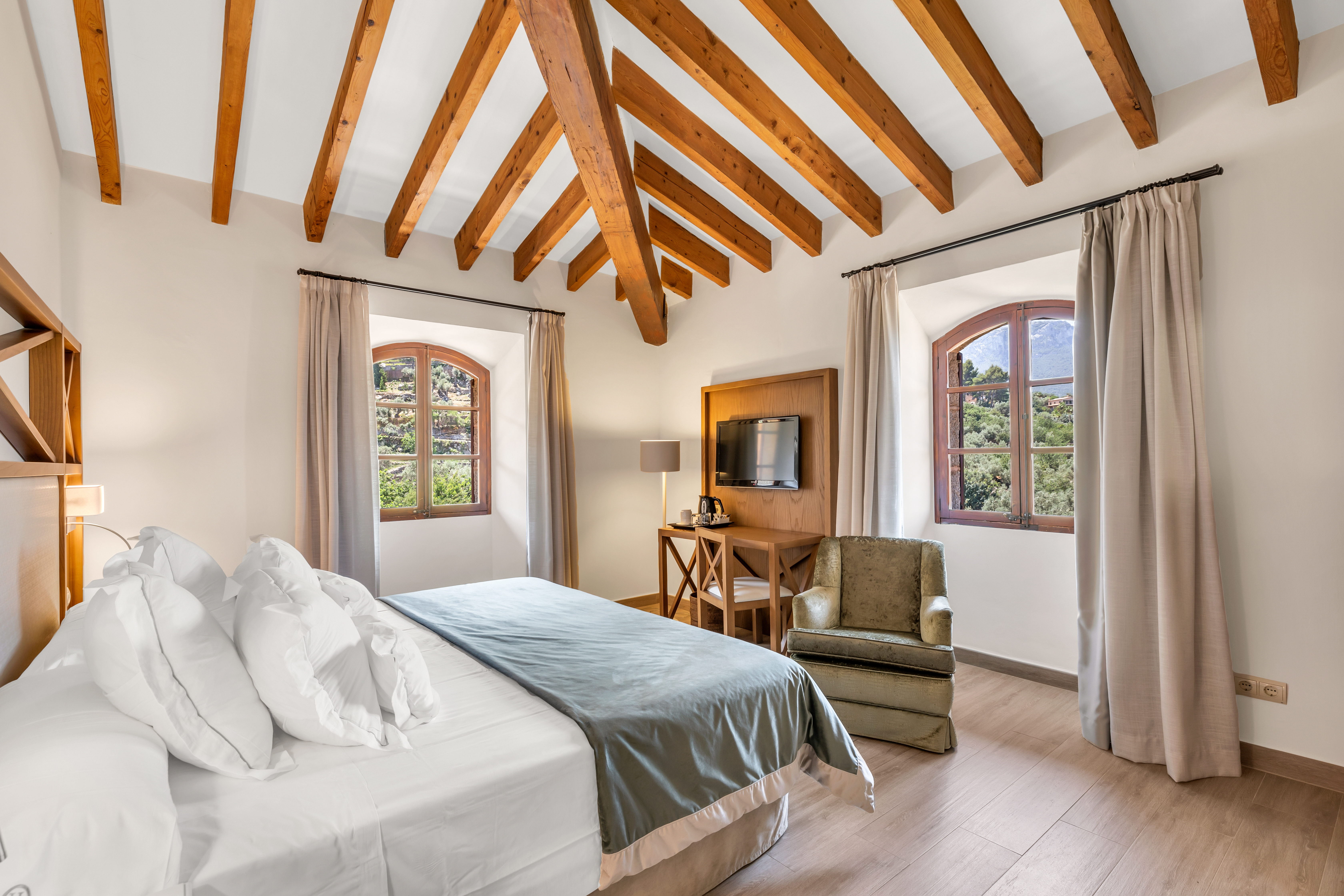 Hotel Hoposa Costa d'Or Standard Room with beamed ceiling, and two arched windows looking out onto the mountains
