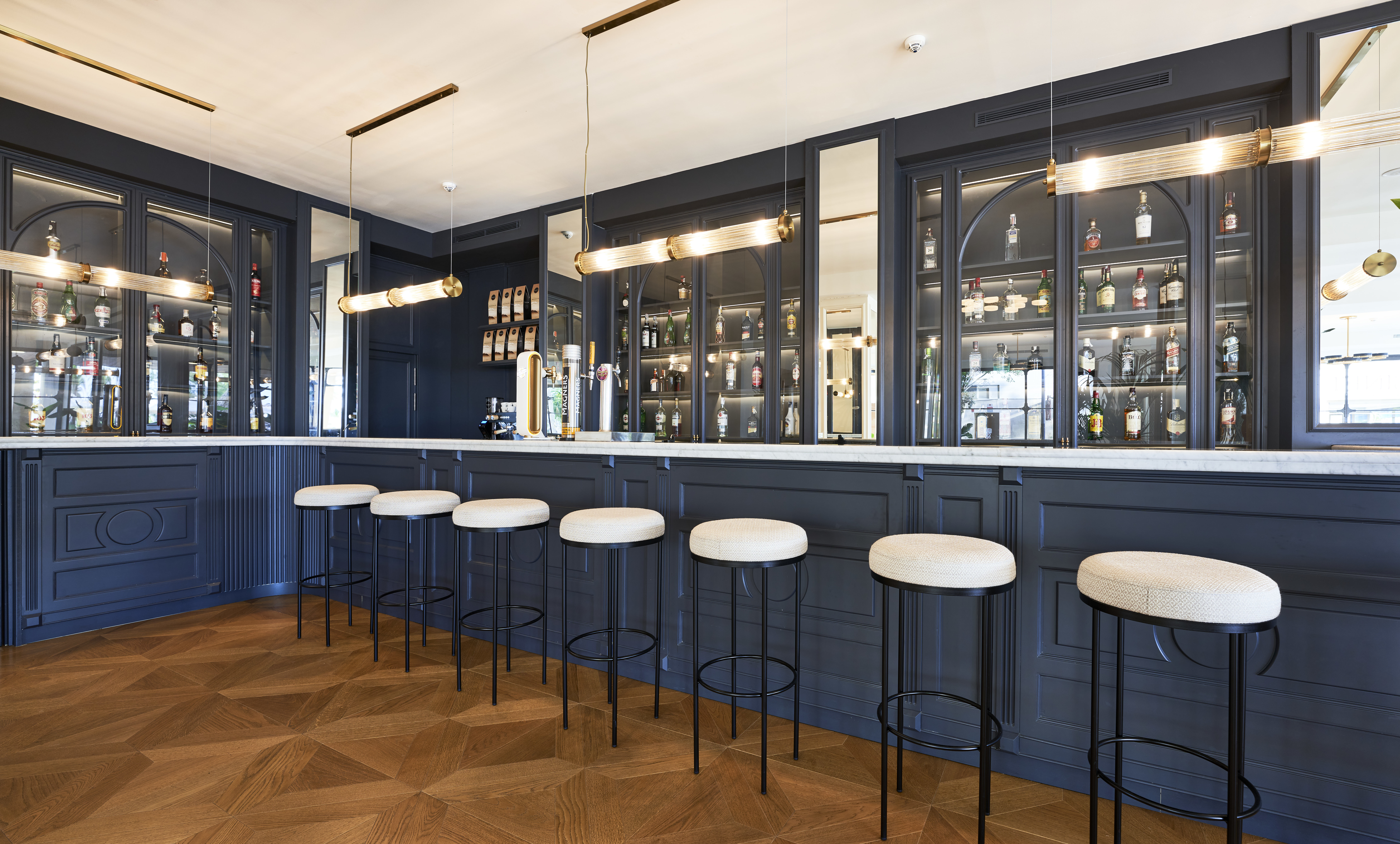 Hotel Hoposa Daina Bar with blue panelling and stylish white-topped black stools