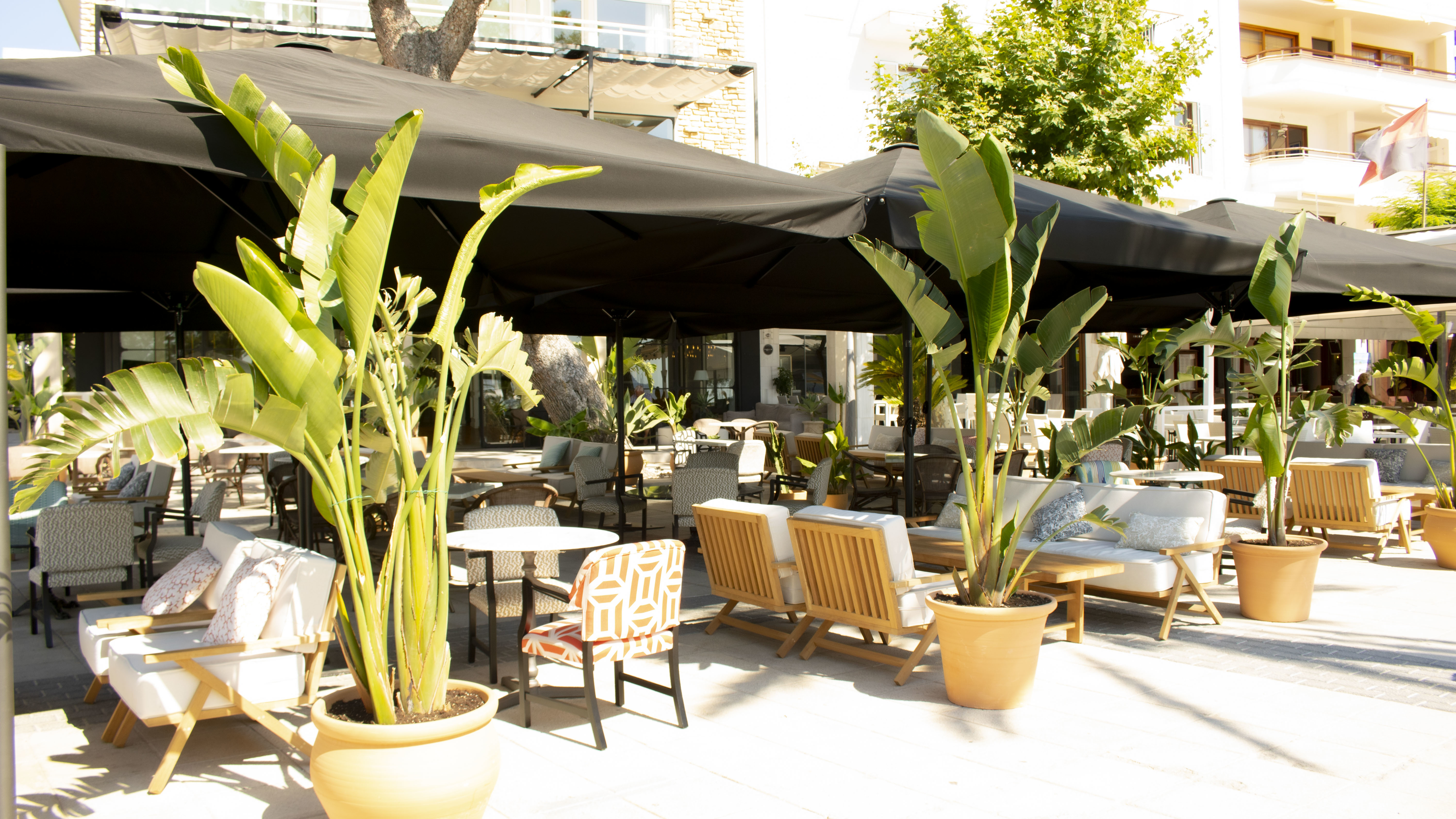 Hotel Hoposa Daina restaurant terrace with large black parasols and comfortable laid-back seating, and potted plants