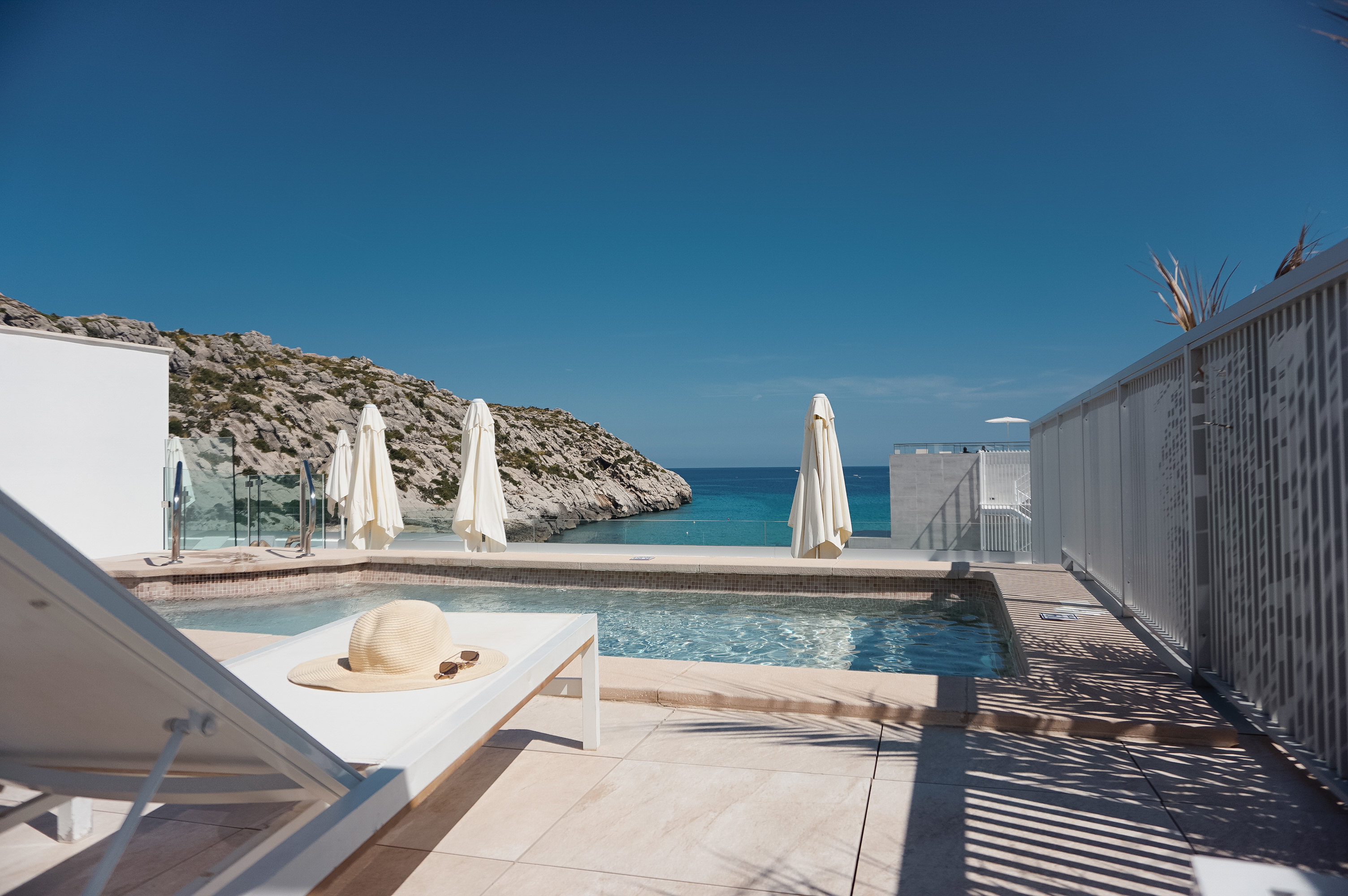 Hotel Hoposa Niu rooftop pool with white loungers and parasols and the sea in the distance