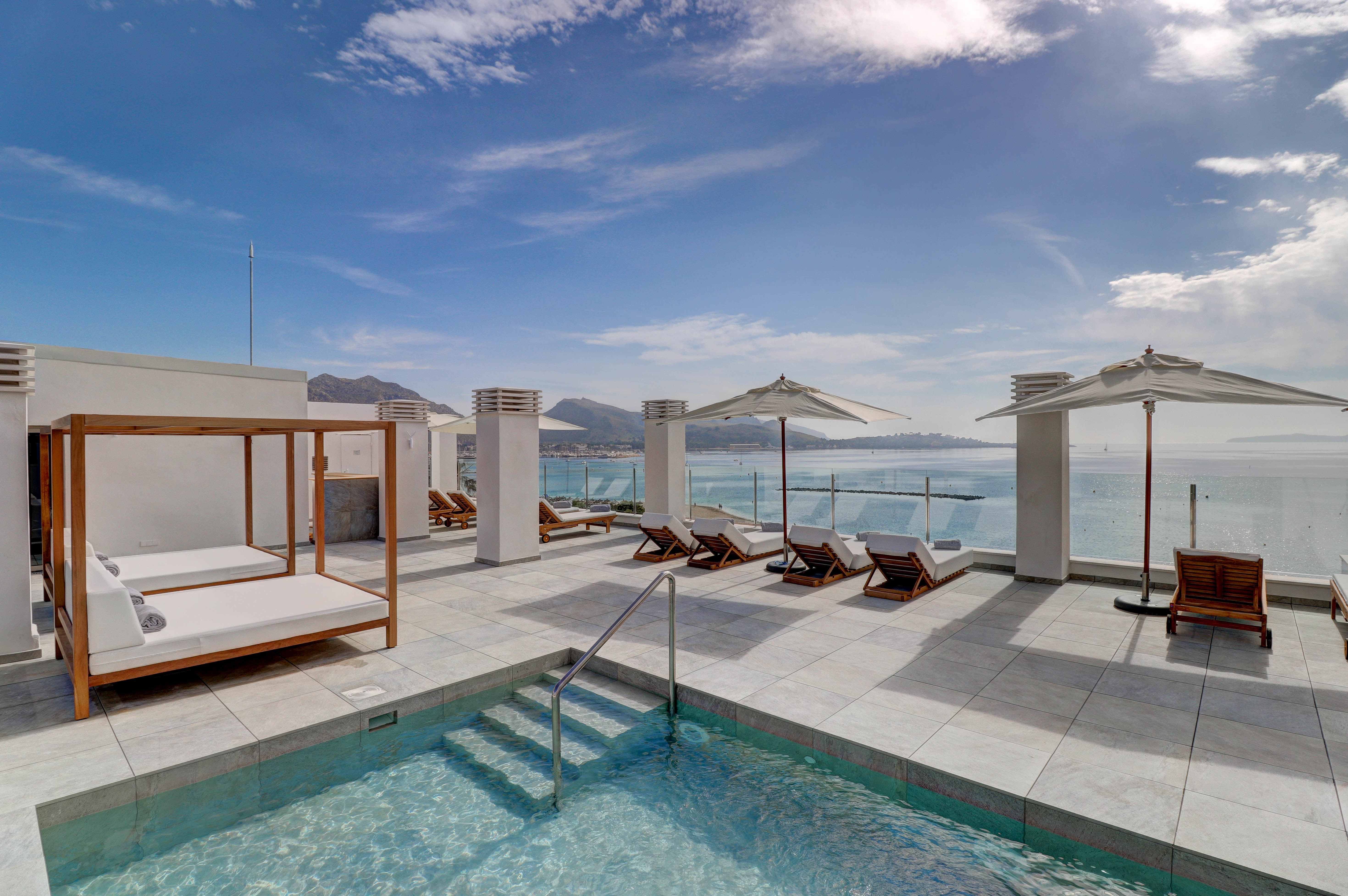 Hotel Hoposa Pollentia swimming pool terrace with canopy beds and loungers looking out towards the sea