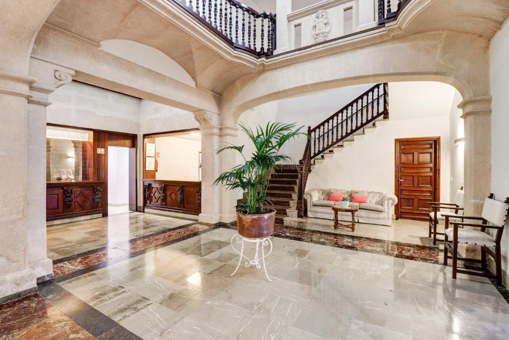 Hotel Hoposa Uyal interior staircase, with white walls, stone arches, and black banisters, winding around the central lobby space