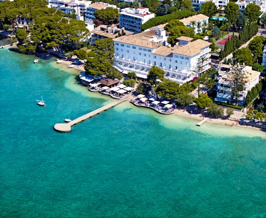 Aerial view of the hotel showing white building and pier over the sea