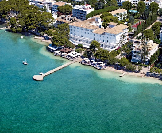 Aerial view of the hotel showing white building and pier over the sea