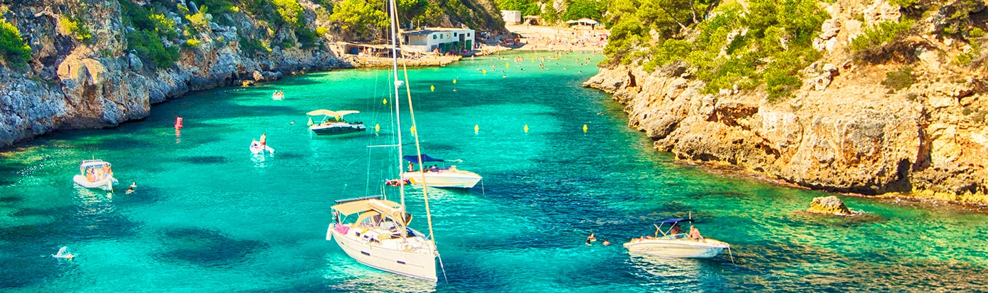 Turquoise waters in rocky cove with moored sailing boats