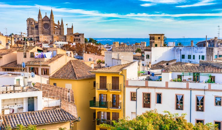 Narrow houses in shades of yellow, white and pink of the old town with rooftops and washing looking to the cathedral in Palma Mallorca