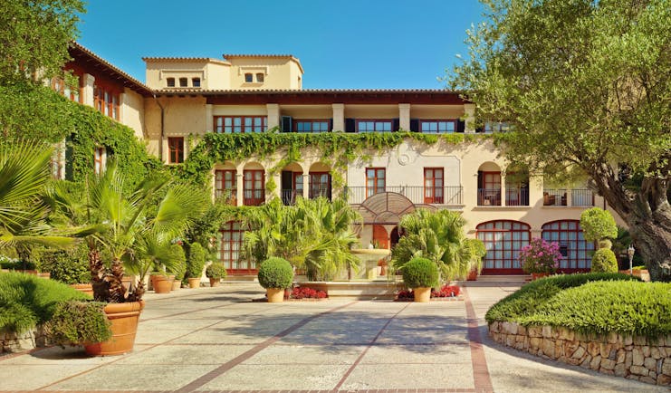 Exterior of hotel with potted plants around and vines on the building