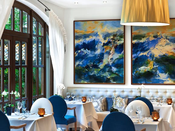 Aqua restaurant with paintings on the walls and blue and white coloured chairs set up 