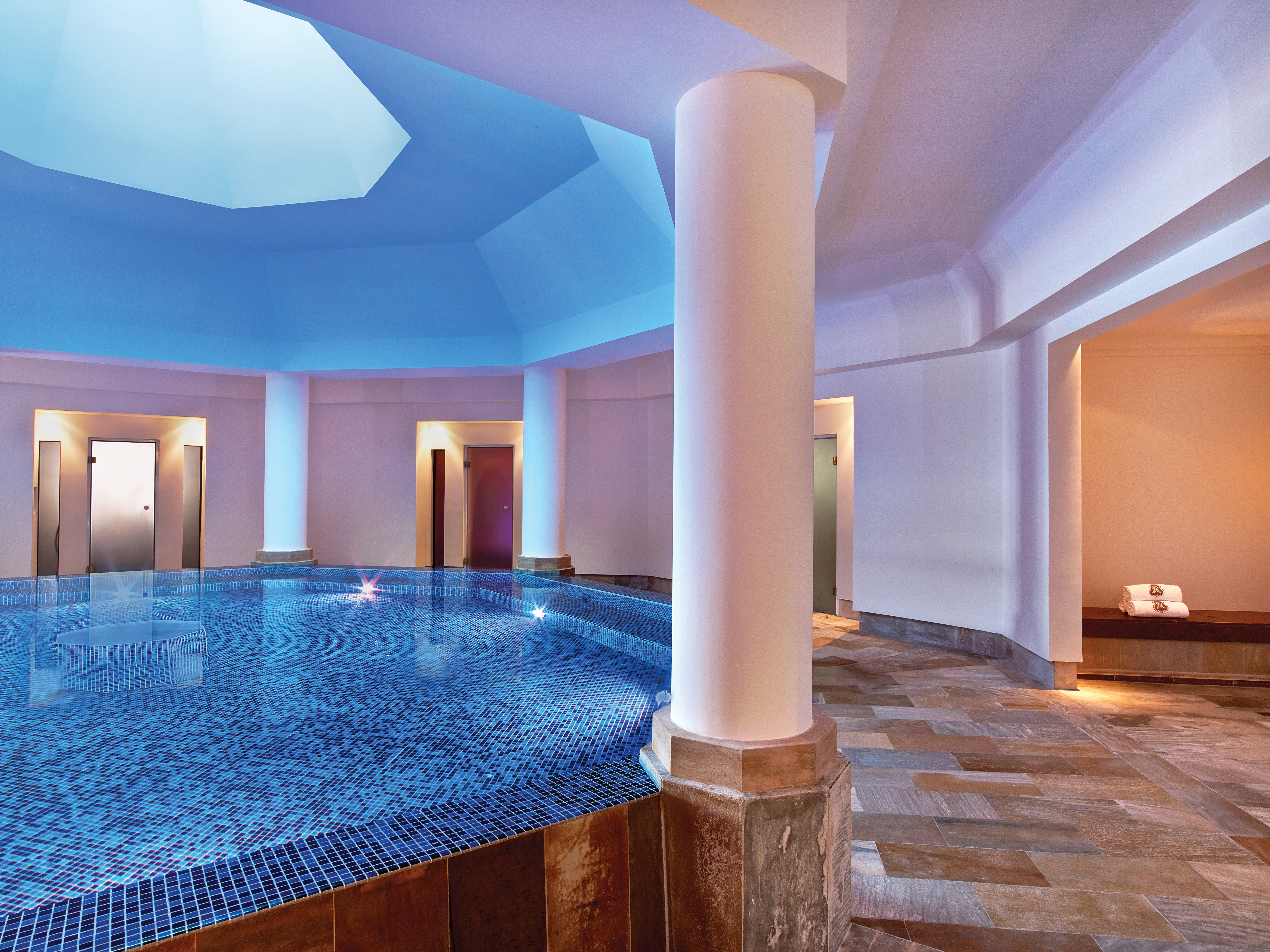 Circular indoor pool with white column pillars 