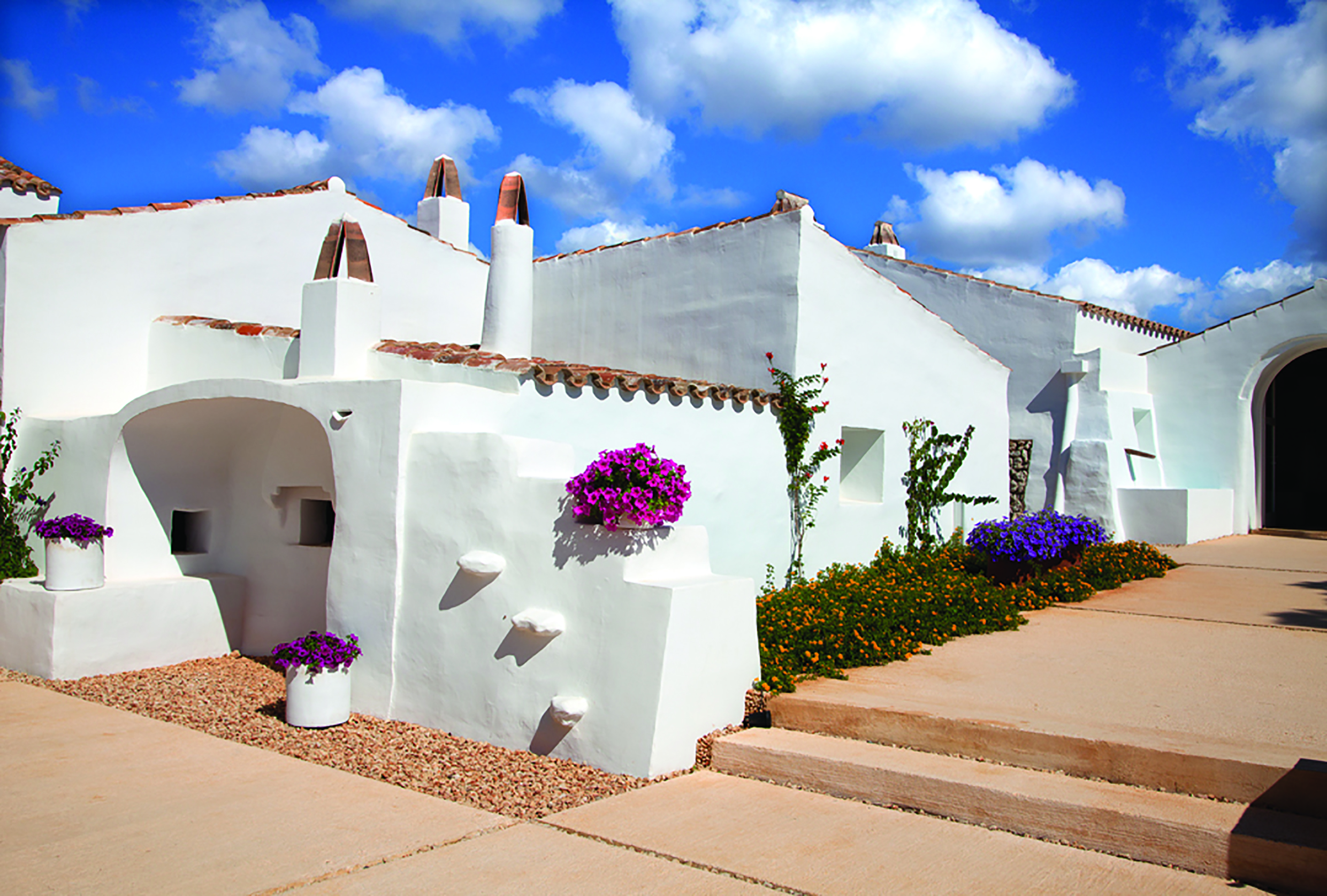 Torralbenc Menorca hotel exterior white buildings pink flowers pathways