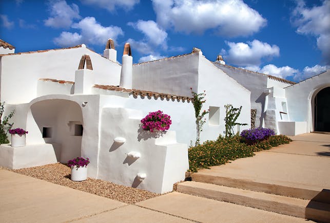 Torralbenc Menorca hotel exterior white buildings pink flowers pathways