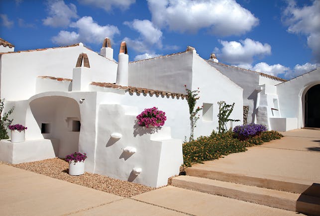 Torralbenc Menorca hotel exterior white buildings pink flowers pathways