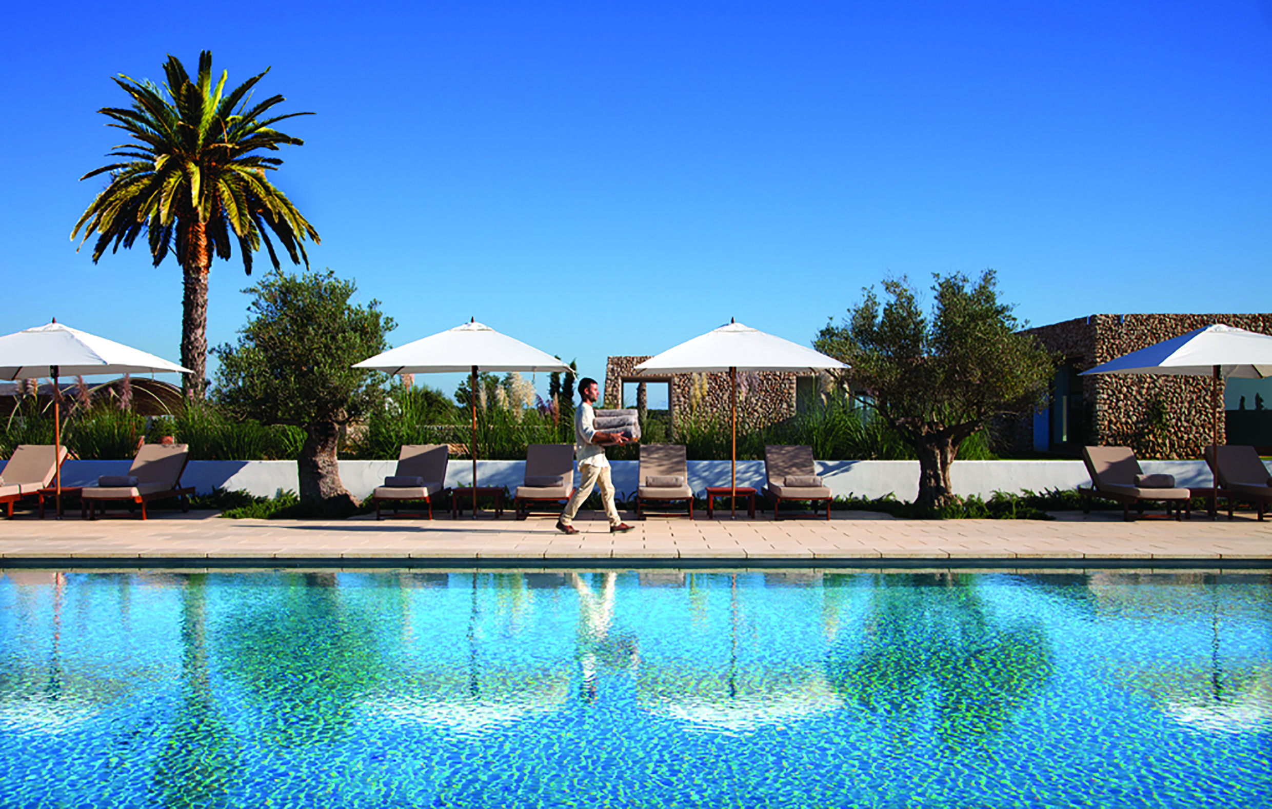 Torralbenc Menorca pool sun loungers umbrellas palm trees