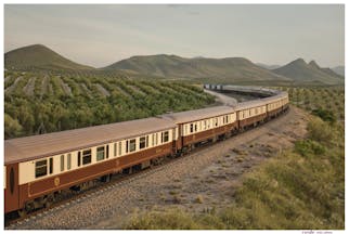 Brown and beige train on track through southern Spanish landcsape