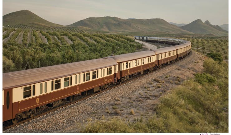 Brown and beige train on track through southern Spanish landcsape