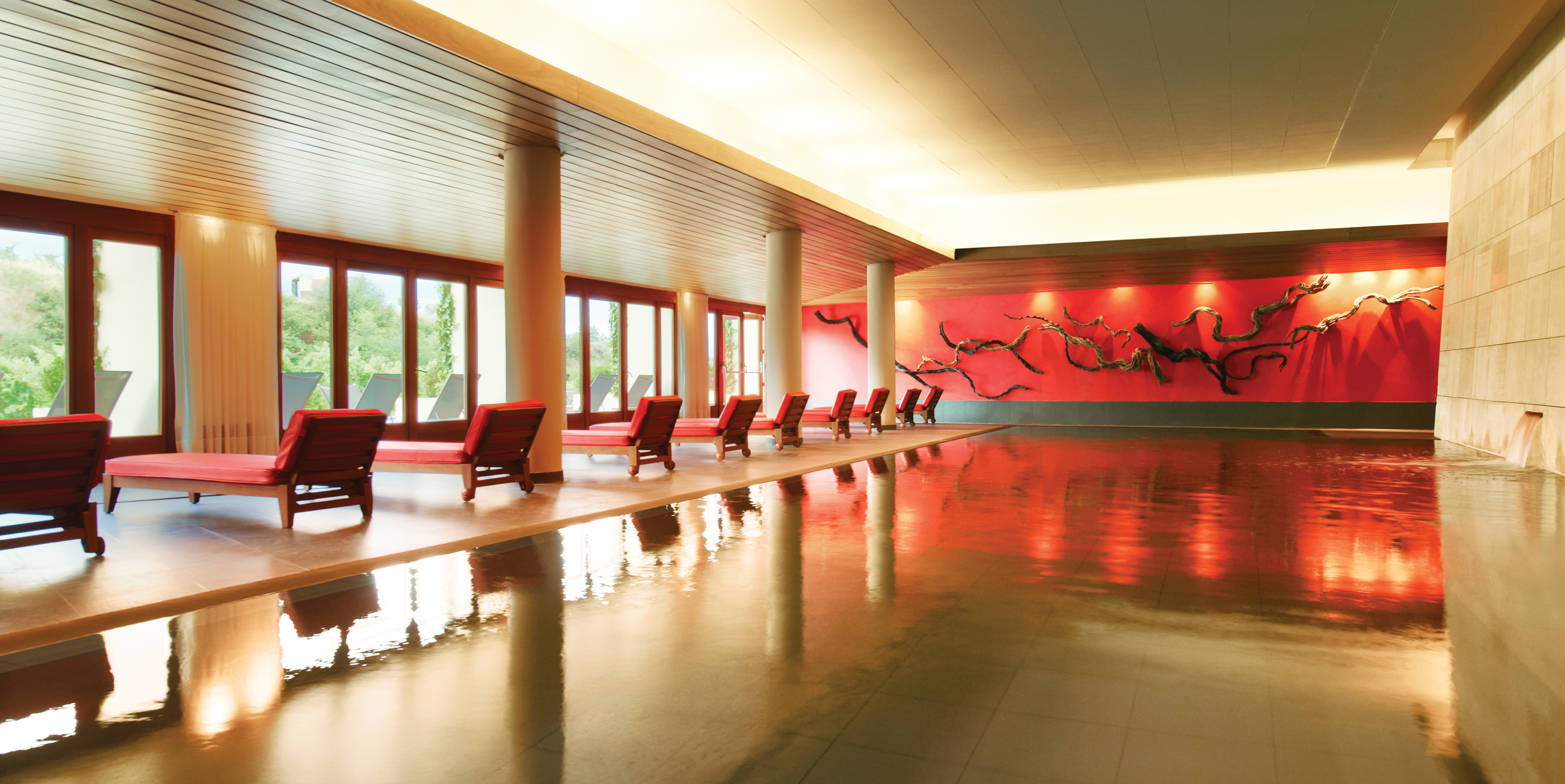 Indoor pool with sun loungers set up around the outside