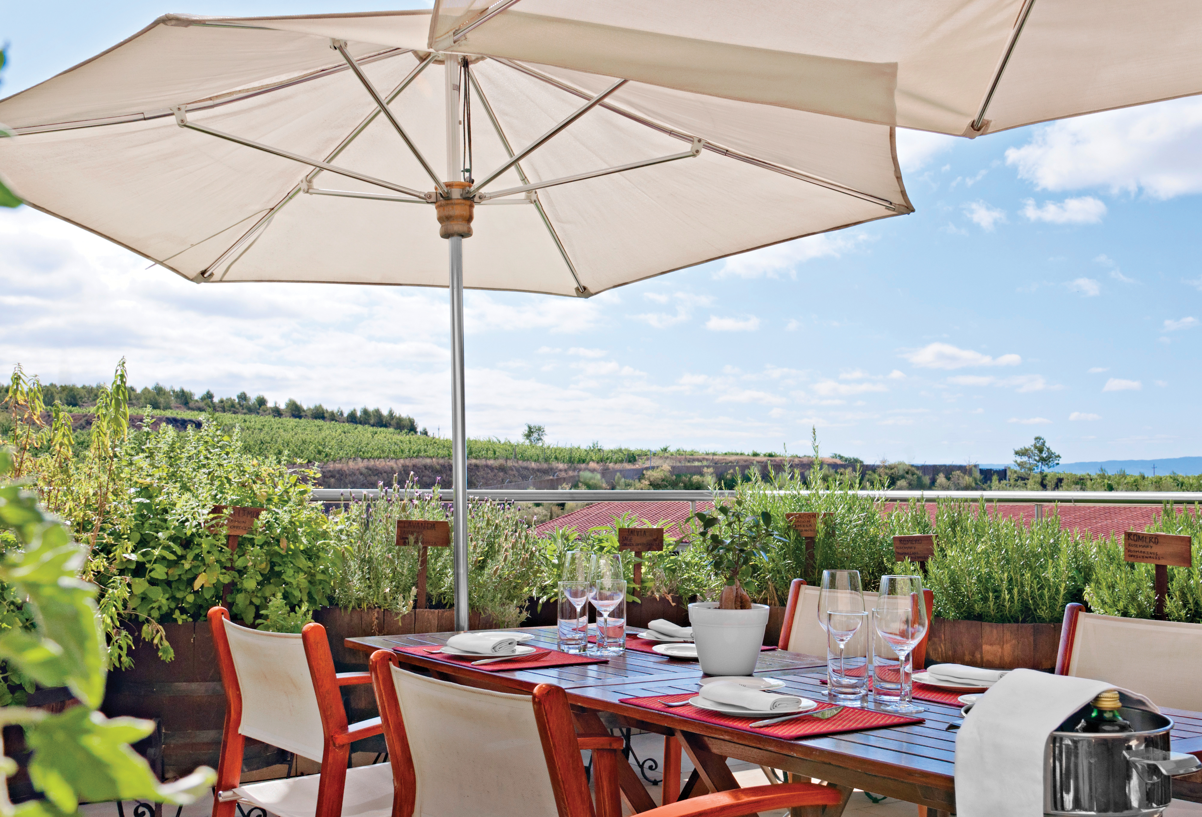 Terrace dining area with tables and chairs set up outside beneath an umbrella