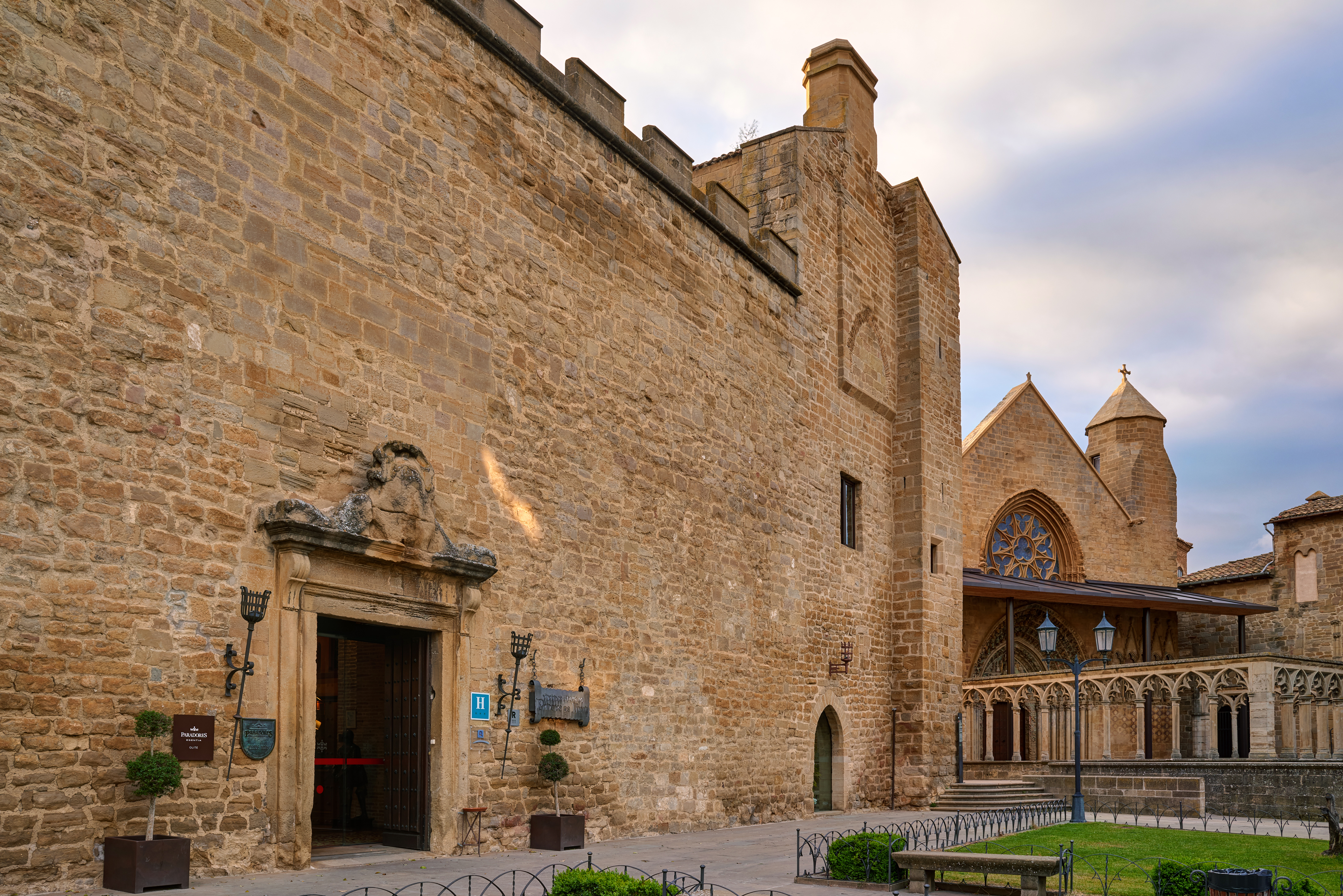 Exterior of the hotel with cobbled stones building, large wooden doors and grassy lawn 