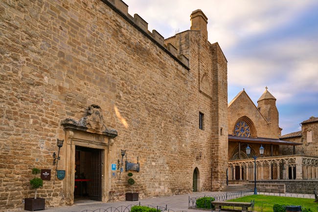 Exterior of the hotel with cobbled stones building, large wooden doors and grassy lawn 