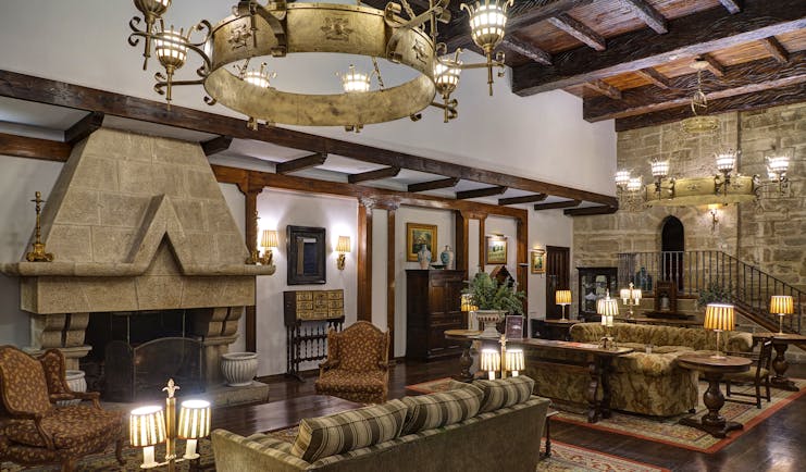 Lounge area with high ceilings, fireplace, large chandeliers, sofas and armchairs