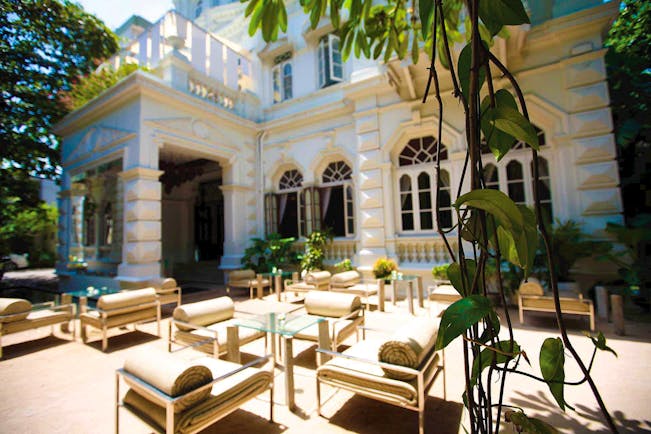 Exterior of hotel during the day with seating areas outside and white hotel building