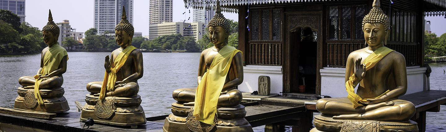 Four golden buddhas on edge of a lake