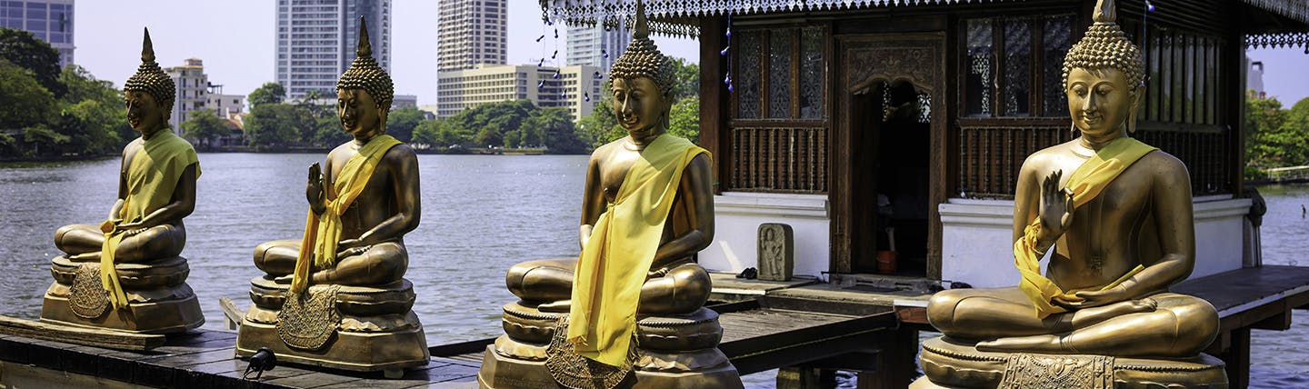 Four golden buddhas on edge of a lake