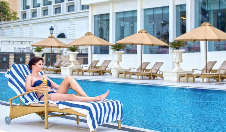 The Kingsbury Sri Lanka pool sun loungers umbrellas lady sun bathing