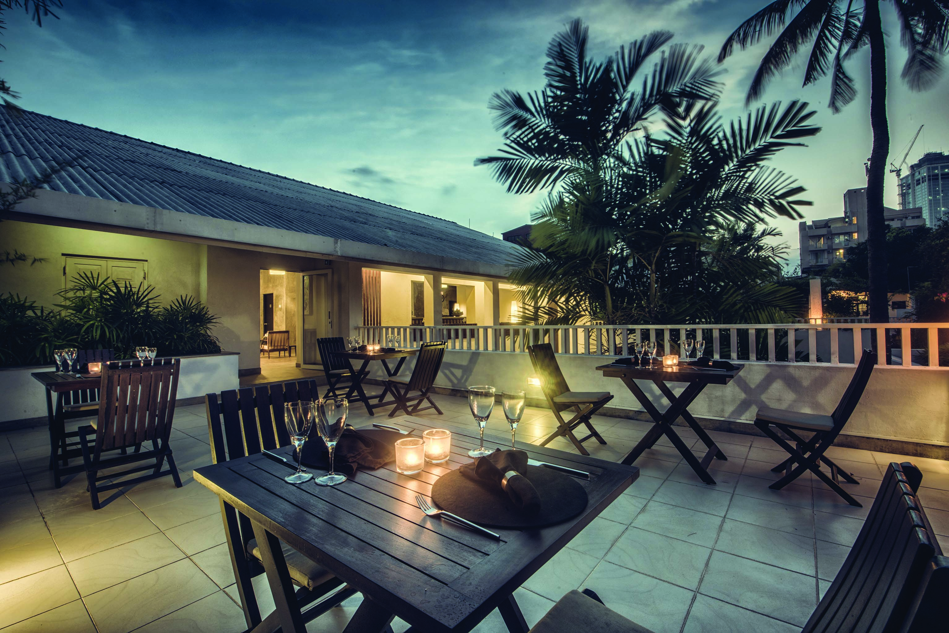 The Lake Lodge dining terrace, tables and chairs, palm trees, city in background