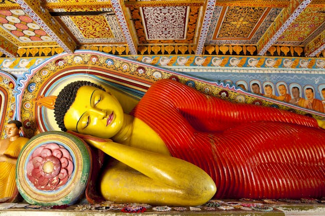 Isurumuniya temple in the Cultural Triangle, colourful buddha statue of Buddha reclining, intricate details