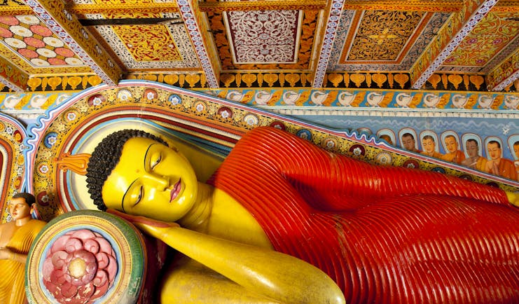 Isurumuniya temple in the Cultural Triangle, colourful buddha statue of Buddha reclining, intricate details