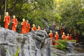 Monk statues, dressed in orange, lining the hillside at the Golden Temple in the Cultural Triangle