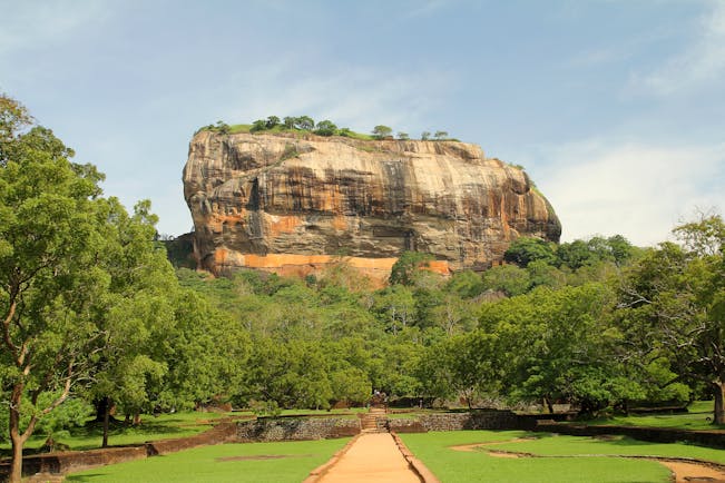 Sigiriya rock in background, trees and grass in foreground