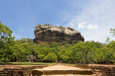 Sigiriya rock surrounded by trees and grassland
