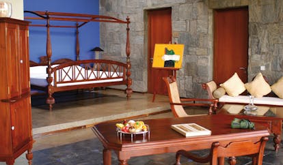 The Elephant Corridor Sri Lanka suite with four poster bed stone walls easel with art lounge area