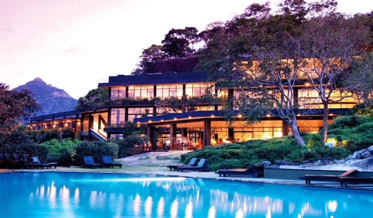 Heritance Kandalama Sri Lanka outdoor pool loungers trees and hotel with large windows sunset