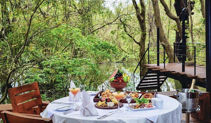 Kalundewa Retreat table on terrace set ofr breakfast with pastries and fresh fruit, views over lake and tree tops
