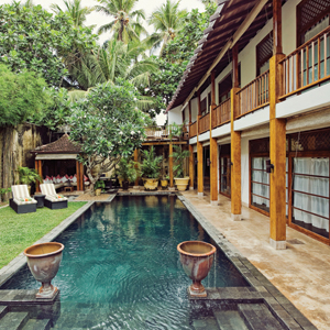 Hotel exterior with a pool, lawn, sunloungers and veranda