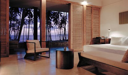 Amanwella Sri Lanka suite bedroom chaise longue chair patio palm trees at sunset