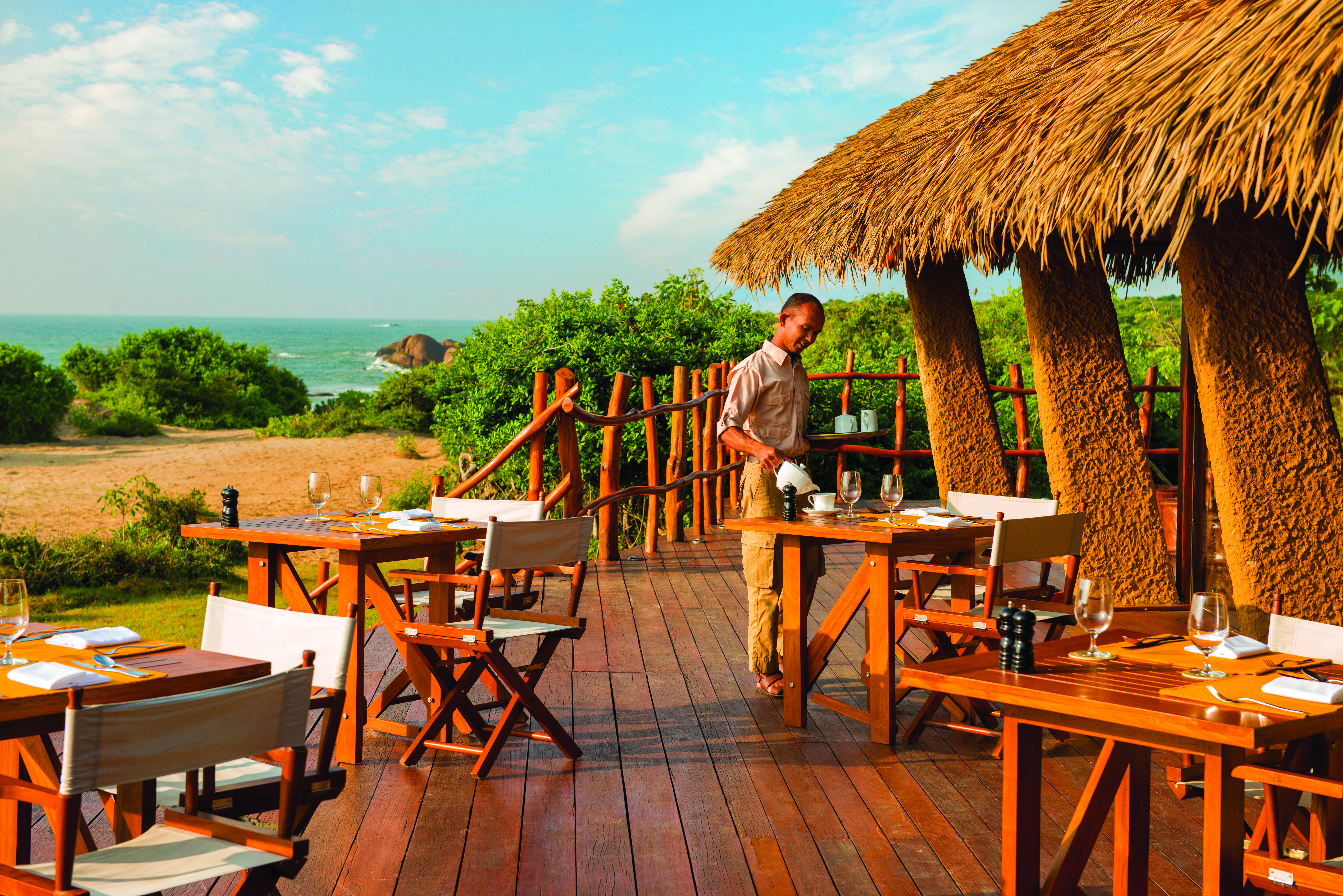Chena Huts dining terrace, tables and chairs on decking, views outover the sea