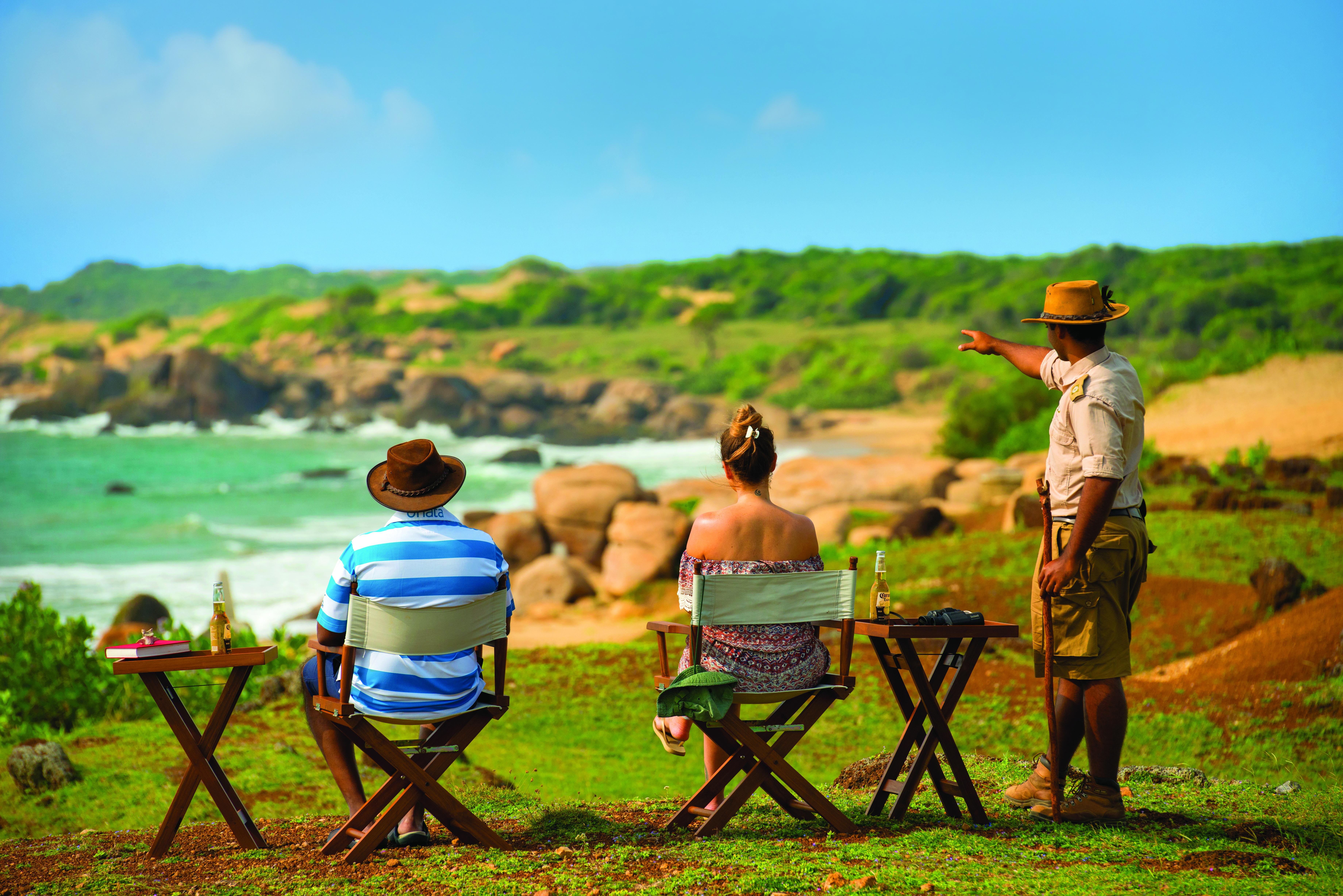 Chena Huts a nature guide telling a couple information about the natural surroundings, views over the sea and coastline
