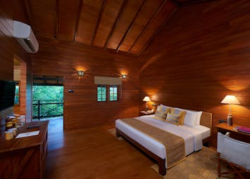 Cinnamon Wild beach chalet, double bed, dresser, wooden walls and ceiling, balcony with tree views