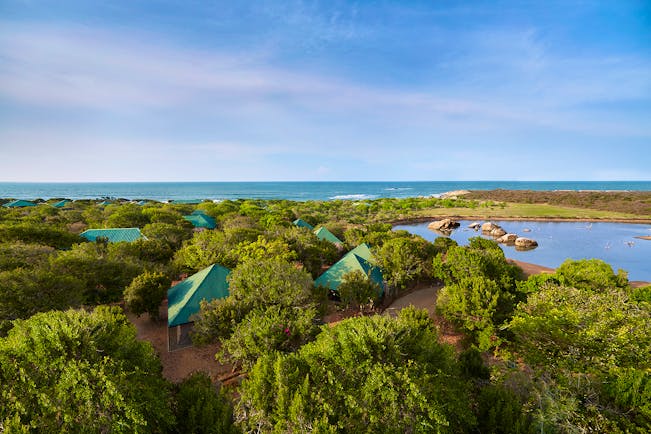 Cinnamon Wild cottages exterior, residences nestled among trees, lake and sea in background