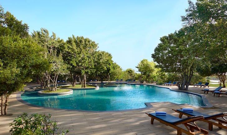 Cinnamon Wild pool, sun loungers on decking, surrounded by tropical trees