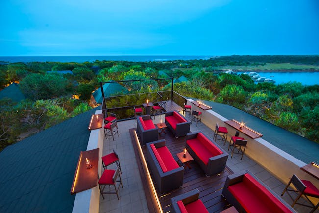 Cinnamon Wild rooftop terrace bar, tables and chairs, sofas, views over countryside, sea in background