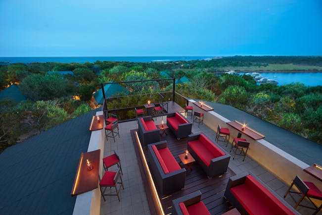 Cinnamon Wild rooftop terrace bar, tables and chairs, sofas, views over countryside, sea in background