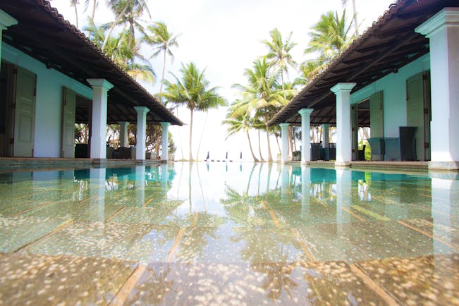 Era Beach Hotel pool, surrounded by columns, palm trees in background