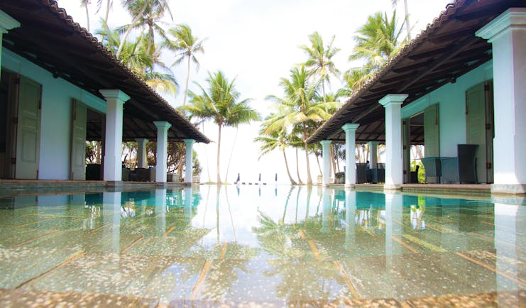 Era Beach Hotel pool, surrounded by columns, palm trees in background