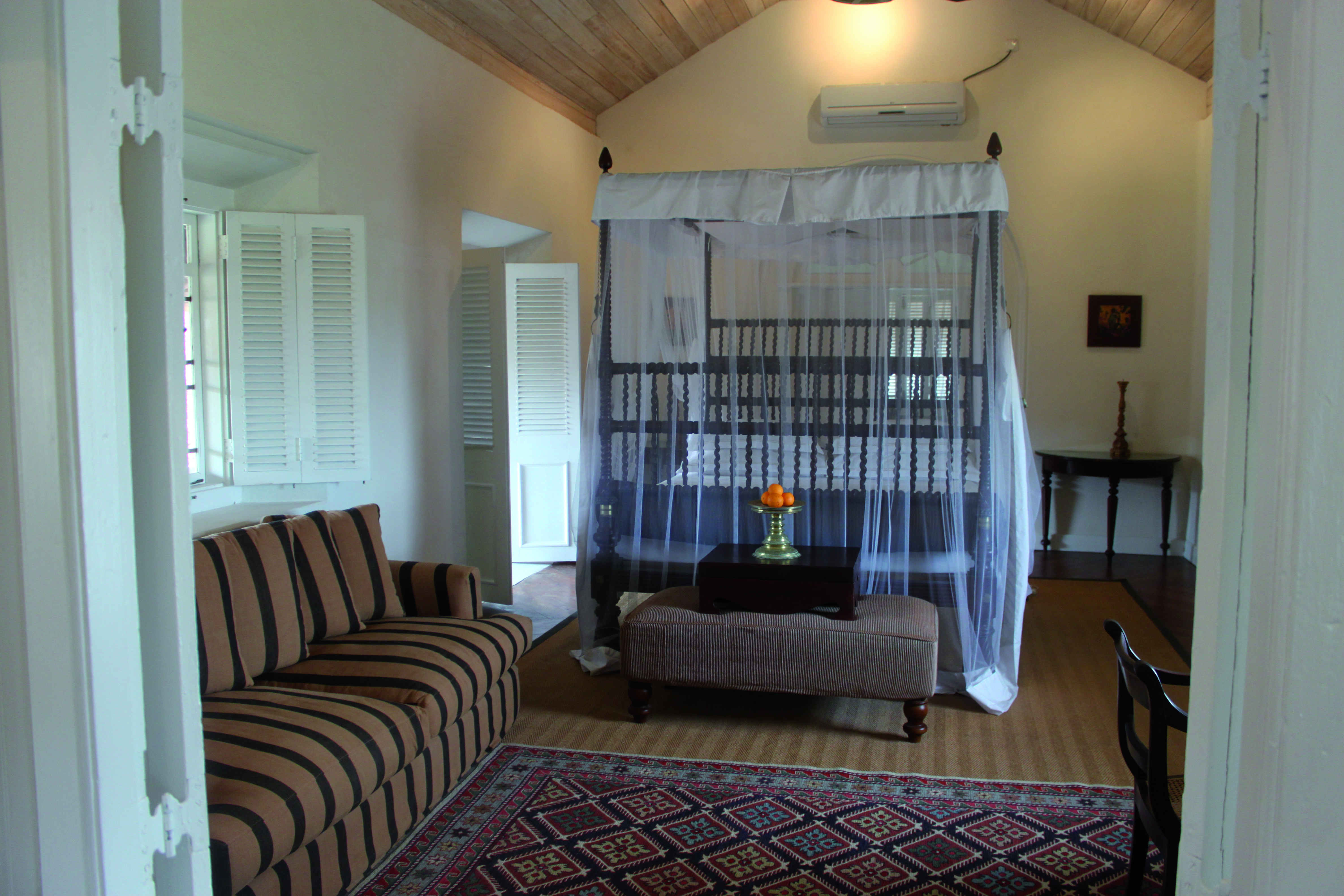 Galle Fort Hotel grand apartment bedroom, canopied bed, foot stall, sofa