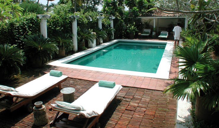 The Sun House Sri Lanka outdoor pool loungers surrounded by greenery